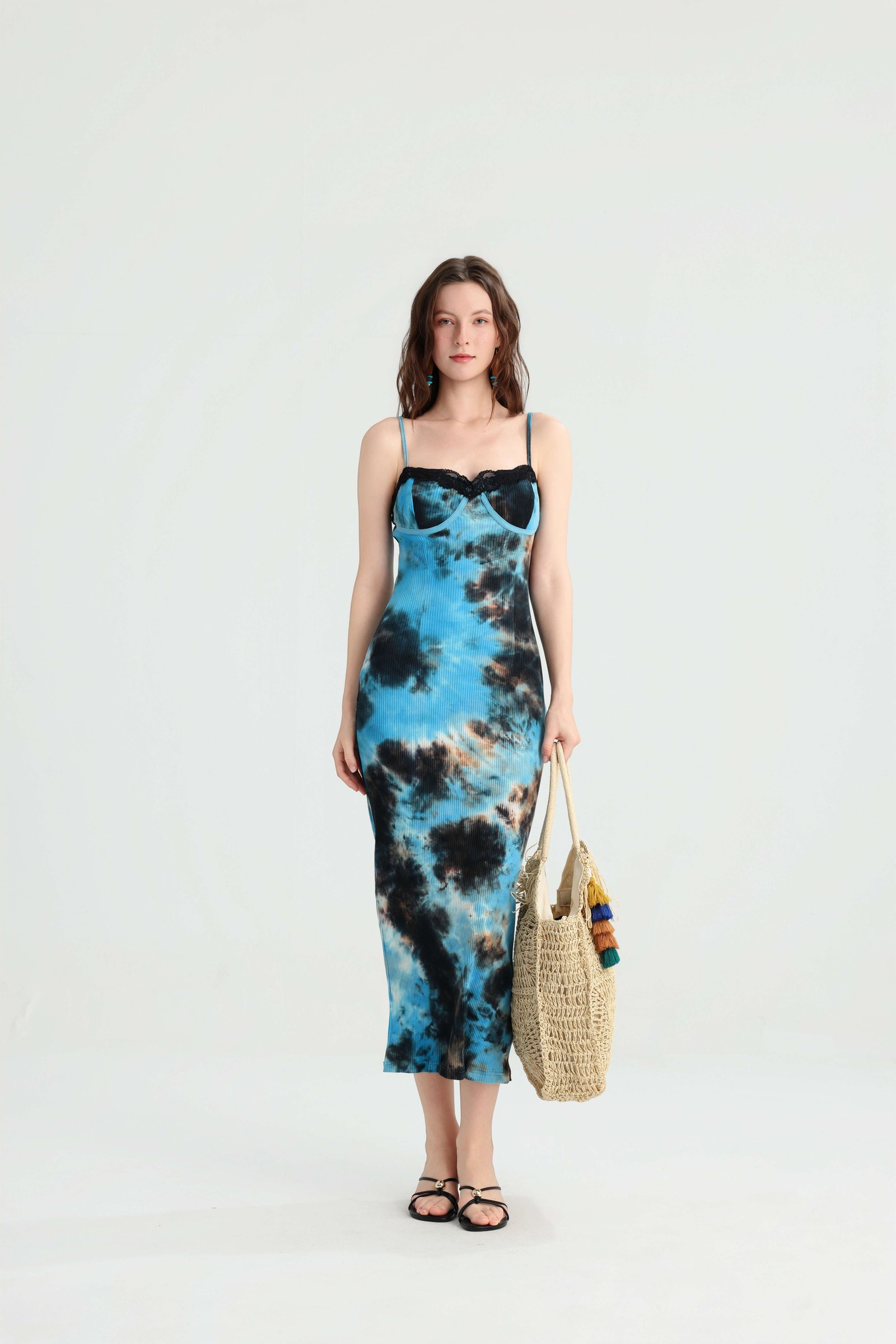 Front view of the blue tie-dye slip dress with a straw tote