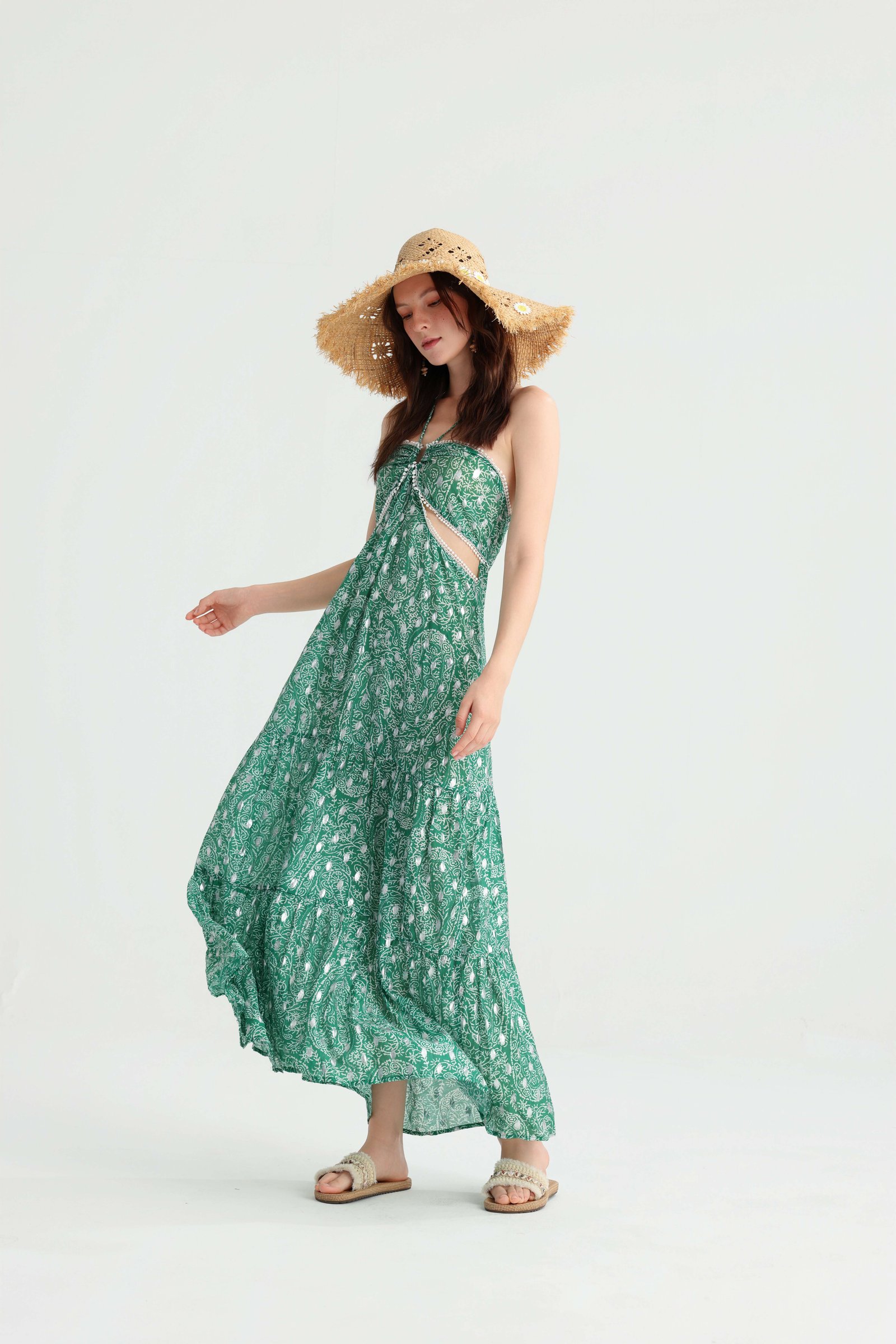 Model wearing a straw hat with the green tiered vacation dress