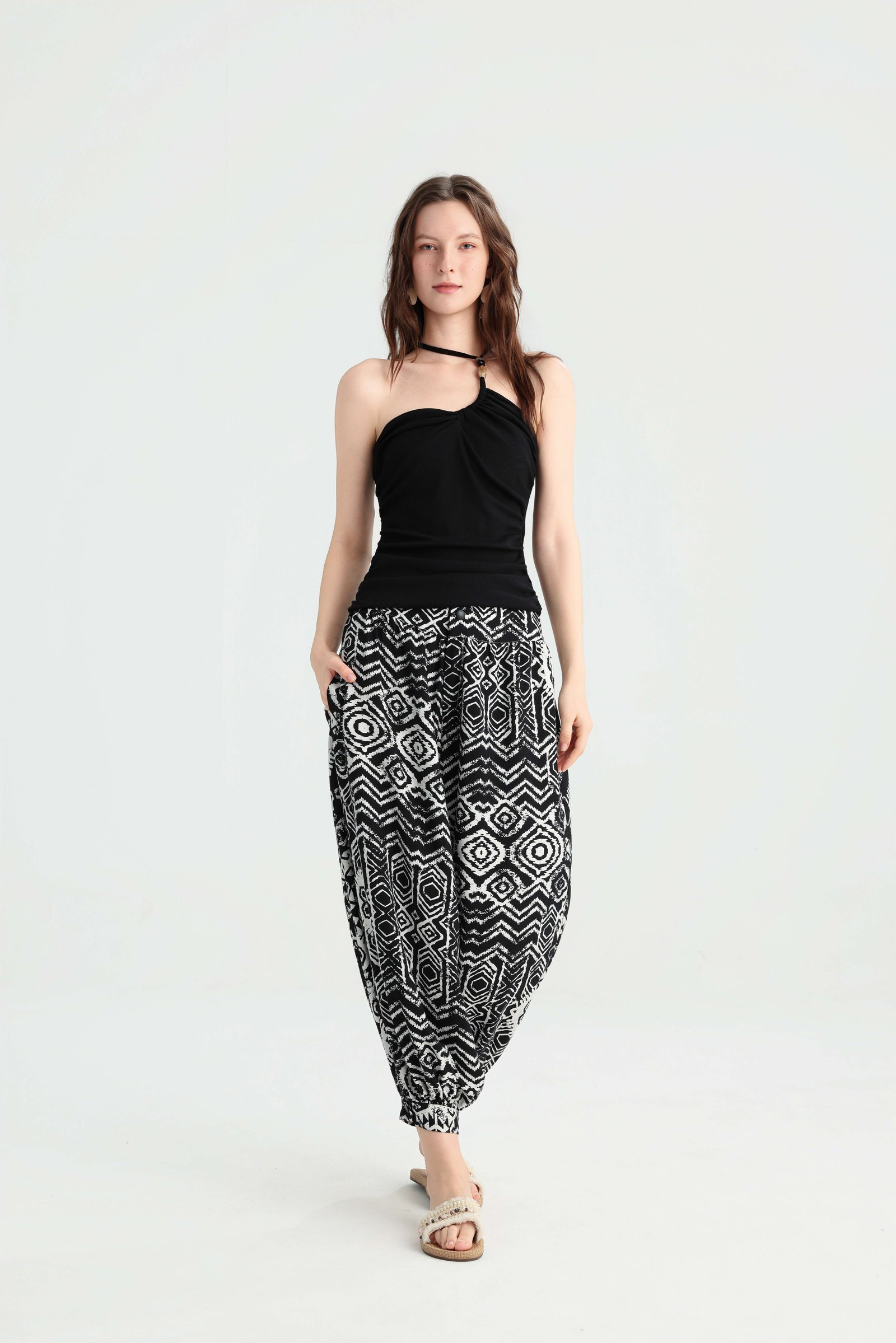 Walking pose in a black halter top and geometric print harem pants