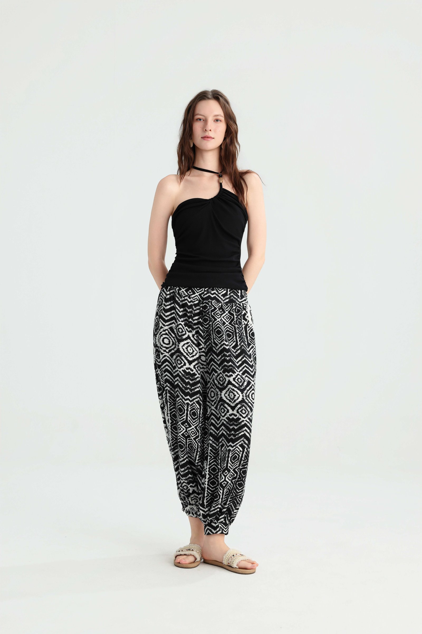 Front view of a black ruched bandeau top with geometric harem pants