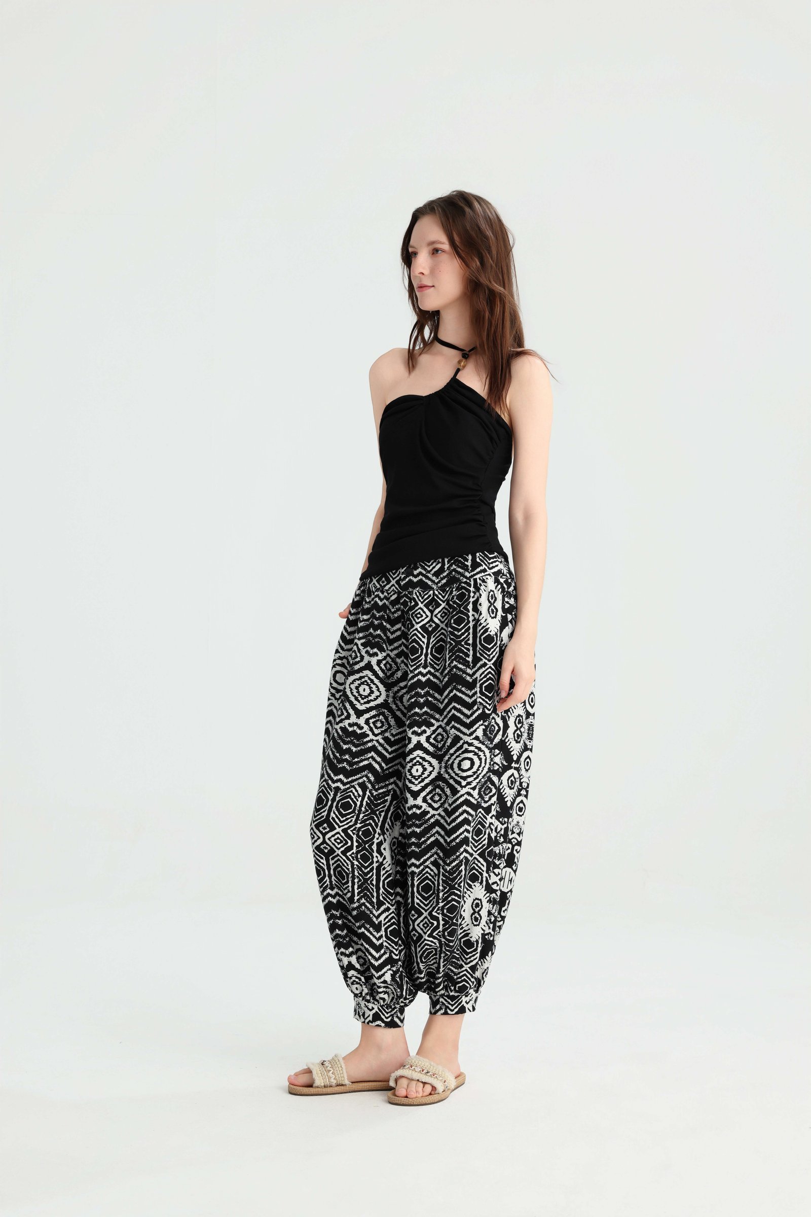 Angled view of a black ruched halter top with geometric pants