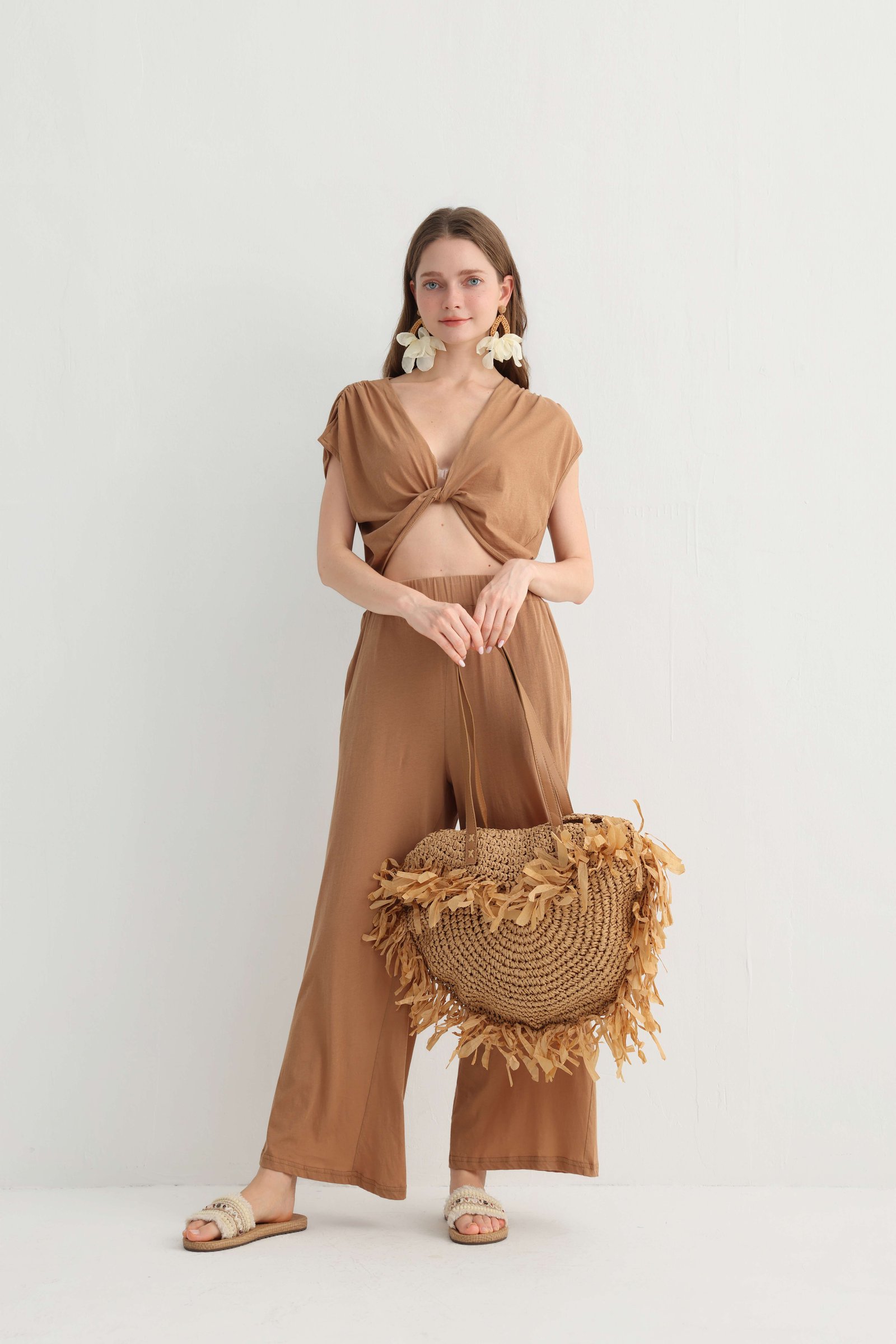 Model holding a straw bag in the camel vacation pants set